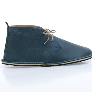 May include: Blue leather ankle boots with a lace-up closure and a cream-coloured sole.
