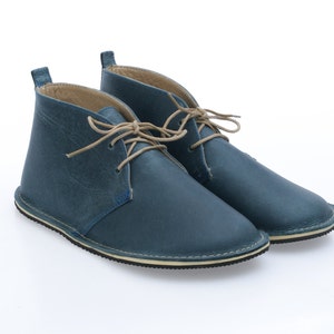May include: A pair of blue leather ankle boots with tan laces. The boots have a rounded toe and a white rubber sole.