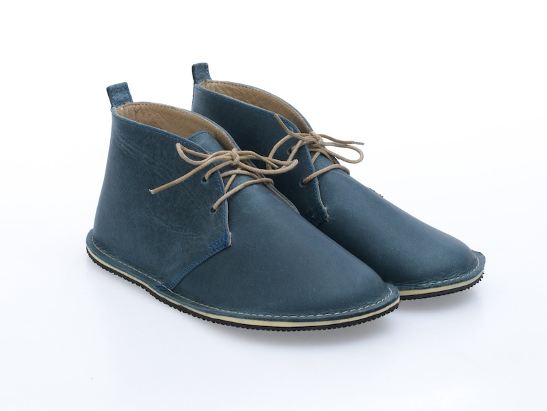 May include: A pair of blue leather ankle boots with tan laces. The boots have a rounded toe and a white rubber sole.