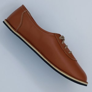 May include: A pair of brown leather lace-up shoes with a white rubber sole.