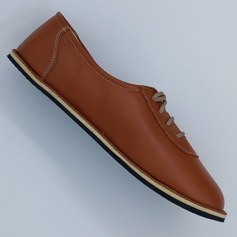 May include: A pair of brown leather lace-up shoes with a white rubber sole.