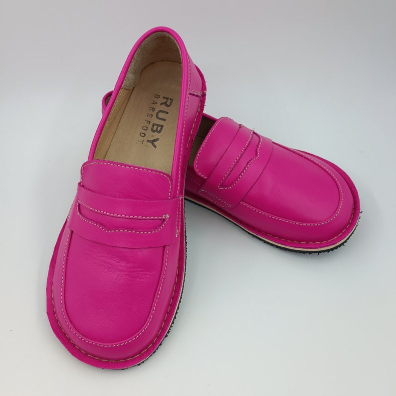 Peut inclure: Une paire de mocassins en cuir rose avec un logo "RUBY BAREFOOT" &agrave; l'int&eacute;rieur de la chaussure gauche.