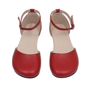 Puede incluir: Un par de zapatos rojos de cuero estilo Mary Jane. Cada zapato tiene una punta redondeada, una correa en el tobillo con hebilla y un tac&oacute;n peque&ntilde;o. Dise&ntilde;ados para la comodidad y el estilo.