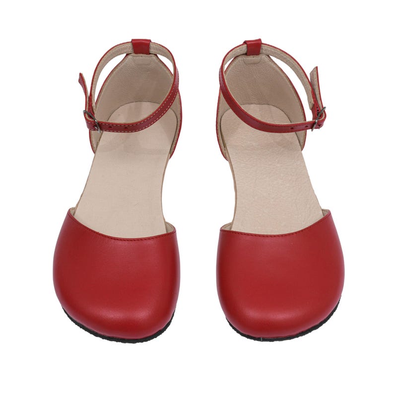 Puede incluir: Un par de zapatos rojos de cuero estilo Mary Jane. Cada zapato tiene una punta redondeada, una correa en el tobillo con hebilla y un tac&oacute;n peque&ntilde;o. Dise&ntilde;ados para la comodidad y el estilo.