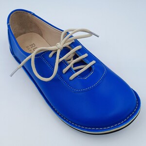 May include: Blue leather lace-up shoes with a white sole and beige laces.