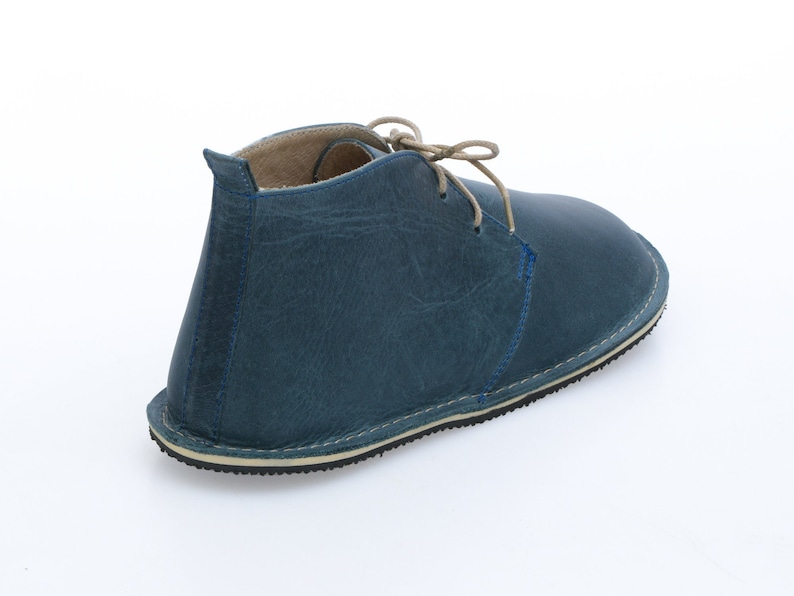 May include: A blue leather ankle boot with a lace-up closure. The boot has a cream-coloured sole and a slightly pointed toe.