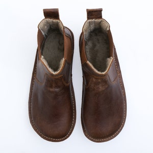 Puede incluir: Un par de botines de cuero marr&oacute;n con forro de ante. Las botas tienen una puntera redonda y un estilo de calcet&iacute;n.