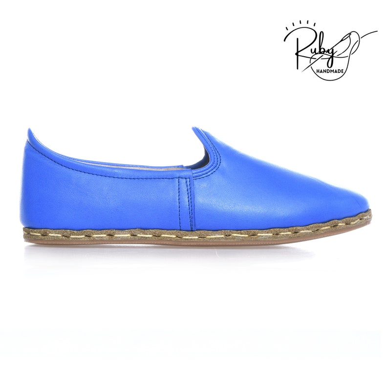 K&ouml;nnte beinhalten: Ein Paar blaue Lederschlappen mit einer braunen, gen&auml;hten Sohle. Die Schuhe sind handgefertigt und haben eine spitze Zehenpartie.