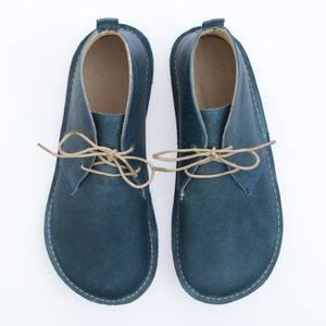 May include: A pair of blue leather ankle boots with tan laces. The boots have a rounded toe and a low heel.