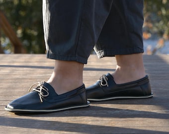 Mocassins minimalistas artesanais em couro preto, com biqueira larga e drop zero.