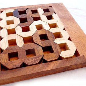 Op de afbeelding: Een houten puzzel met een frame en 12 in elkaar grijpende stukken. De stukken zijn in twee tinten bruin, licht en donker. De puzzel is samengesteld in een patroon van afwisselende lichte en donkere stukken.