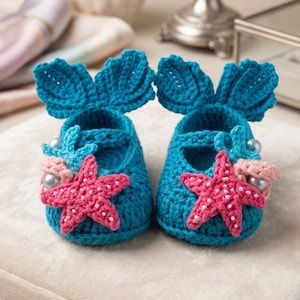 Peut inclure: Une paire de chaussons de b&eacute;b&eacute; en crochet turquoise. Chaque chausson est orn&eacute; d'une &eacute;toile de mer rose, d'un petit hippocampe bleu et d'un coquillage rose avec des perles. Les chaussons ont une forme de nageoire &agrave; l'arri&egrave;re.