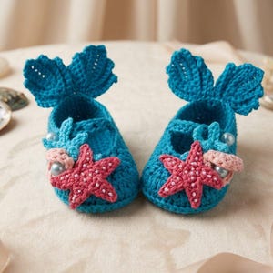 Peut inclure: Une paire de chaussons de b&eacute;b&eacute; au crochet turquoise. Chaque chausson pr&eacute;sente une &eacute;toile de mer rose, des perles et un d&eacute;tail en forme d'aileron. Ces chaussons faits &agrave; la main ont un th&egrave;me de sir&egrave;ne.