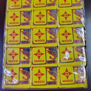 May include: A box of 20 yellow and red Maggi Crayfish bouillon cubes. The cubes are individually wrapped in plastic.