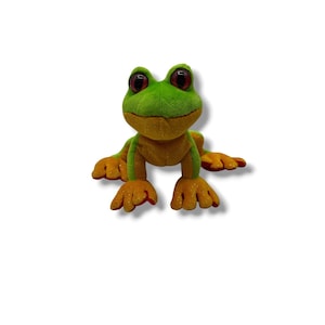 Puede incluir: Un juguete de peluche con forma de rana con cabeza y espalda verdes, vientre amarillo y pies naranjas. La rana tiene ojos grandes con bordes rojos y una expresión amigable. El juguete está diseñado para sentarse erguido.