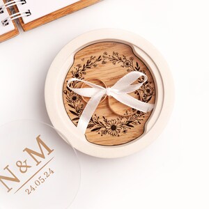 An alternative ring box made of white plaster with an oak insert engraved with a wreath with daisies.