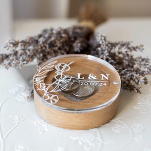 Personalized oak engagement ring holder with transparent acrylic cover and rustic linen cushion.