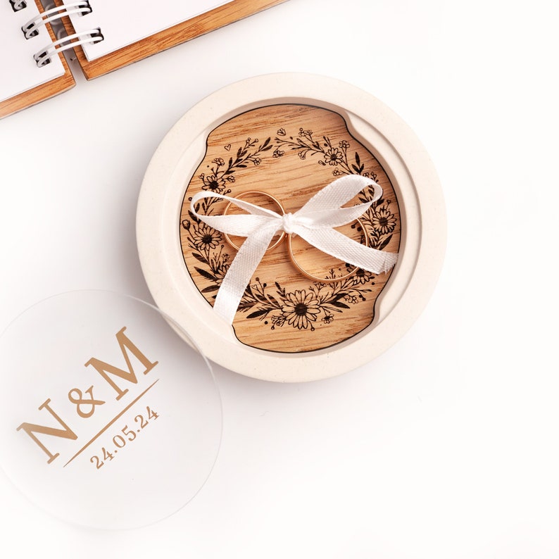 An alternative ring box made of white plaster with an oak insert engraved with a wreath with daisies.