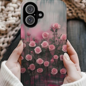 Peut inclure: Une coque de téléphone avec un motif floral rose et gris avec des roses roses. La coque a une découpe pour l'objectif de l'appareil photo noir.