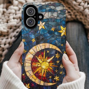 May include: A phone case with a stained glass design featuring a crescent moon, a sun, and stars on a blue background.