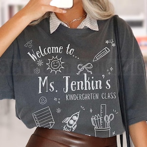 Camiseta com o nome do professor de jardim de infância, camiseta personalizada com cartão-postal de volta às aulas, camiseta com rabiscos para cada série, camiseta Comfort Colors Teach Kinder