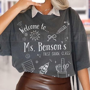 Camiseta com o nome do professor da primeira série, camiseta personalizada com cartão-postal de volta às aulas, camiseta com rabiscos para cada série, camiseta Comfort Colors Teach 1st