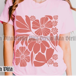 May include: A pink t-shirt with a floral design in shades of red. The design features stylized flowers and leaves.