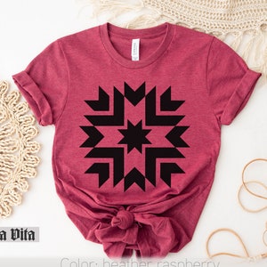 May include: A heather raspberry t-shirt with a black geometric starburst design. The shirt is made of a soft, comfortable material.