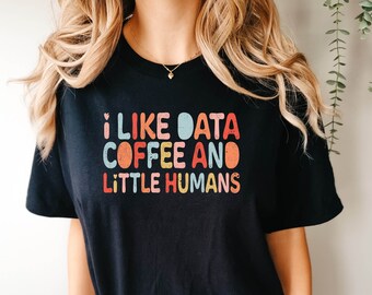 May include: Black t-shirt with a colorful graphic that says "I like data coffee and little humans".