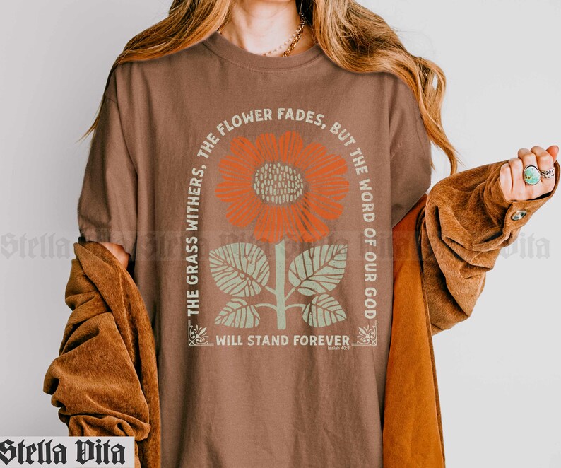 May include: A brown t-shirt with a graphic of a sunflower and the text "The grass withers, the flower fades, but the word of our God will stand forever."