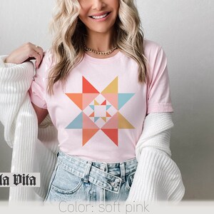 May include: A soft pink t-shirt with a colorful geometric star design. The text "Stella Vita" is visible at the bottom of the image.