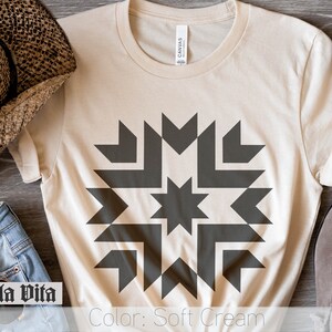 May include: A soft cream colored t-shirt with a dark gray geometric design featuring a star in the center. The text "Color: Soft Cream" is printed at the bottom of the image.