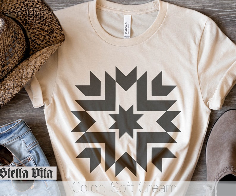 May include: A soft cream colored t-shirt with a dark gray geometric design featuring a star in the center. The text "Color: Soft Cream" is printed at the bottom of the image.