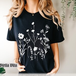 Minimalistisk blommig t-shirt, Komfortfärgad t-shirt, Vit negrös t-shirt med rymdblommor, Vildblommig t-shirt, Boho grafiska t-shirts för kvinnor, Blommig t-shirt bild 2