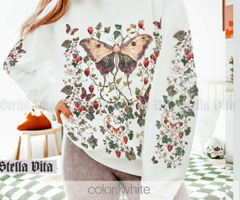 May include: White sweatshirt with a large butterfly and floral print. The butterfly is brown, green, and purple with red and white strawberries throughout the design.