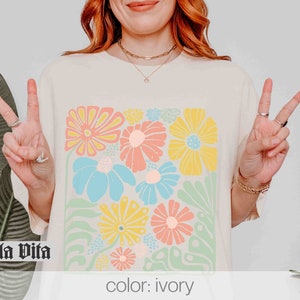 Peut inclure: Un t-shirt cr&egrave;me avec un imprim&eacute; floral color&eacute;. L'imprim&eacute; pr&eacute;sente une vari&eacute;t&eacute; de fleurs dans des tons de rose, jaune, bleu et vert. Le texte "Stella Vita" est imprim&eacute; en noir dans le coin inf&eacute;rieur gauche du t-shirt. Le texte "color: ivory" est imprim&eacute; dans le coin inf&eacute;rieur droit du t-shirt.