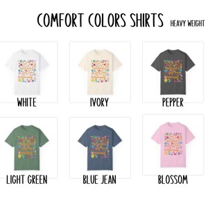 May include: Six different colour t-shirts with a colourful graphic print that says "Comfort Colors Shirts" in a rainbow font. The colours are white, ivory, pepper, light green, blue jean, and blossom. The shirts are heavy weight.