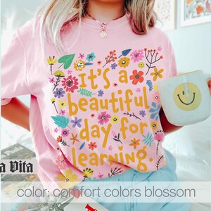 May include: Pink t-shirt with a floral design and the text "It's a beautiful day for learning".