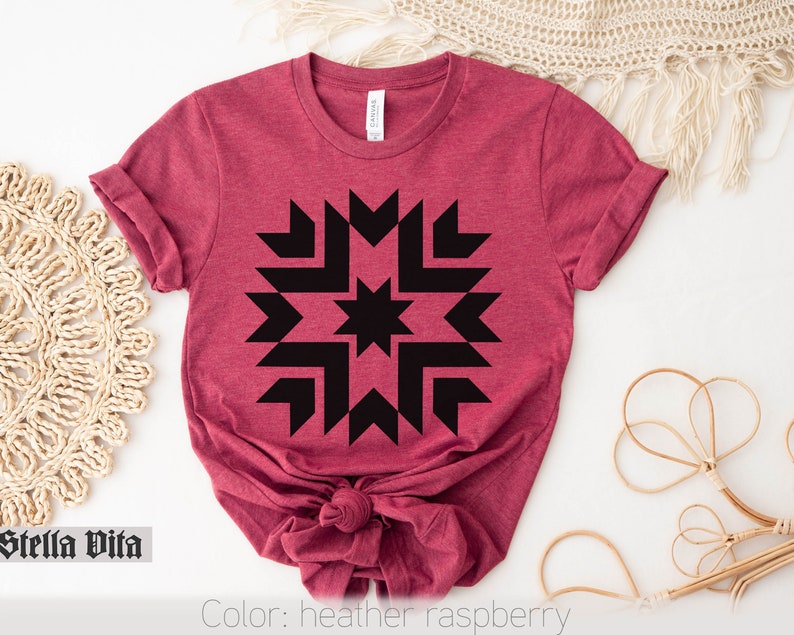 May include: A heather raspberry t-shirt with a black geometric starburst design. The shirt is made of a soft, comfortable material.
