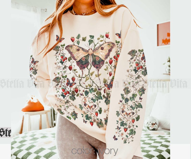 May include: A cream-colored sweatshirt with a floral print featuring butterflies and strawberries. The print is in shades of red, green, and brown.