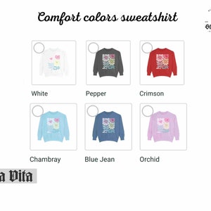 May include: A sweatshirt with a floral design is shown in ten different colours: white, pepper, crimson, Chambray, blue jean, orchid, black, navy, forest green, and burgundy. The text "Comfort colours sweatshirt" is at the top of the image. The text "Stella Vita" is at the bottom of the image.