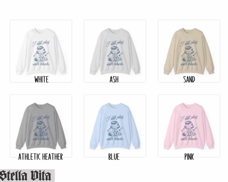 K&ouml;nnte beinhalten: Ein Set aus zehn Crewneck-Sweatshirts in verschiedenen Farben mit einem Motiv eines M&auml;dchens, das mit Bl&ouml;cken spielt, und dem Text "I still play with blocks". Die Farben umfassen Wei&szlig;, Asche, Sand, Sport-Heather, Blau und Pink.