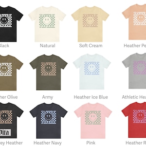 May include: A collection of t-shirts in various colors featuring a white checkered pattern with a smiley face and the text "It's a beautiful day to spread kindness".