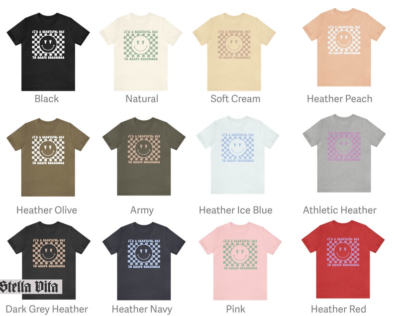 May include: A collection of t-shirts in various colors featuring a white checkered pattern with a smiley face and the text "It's a beautiful day to spread kindness".