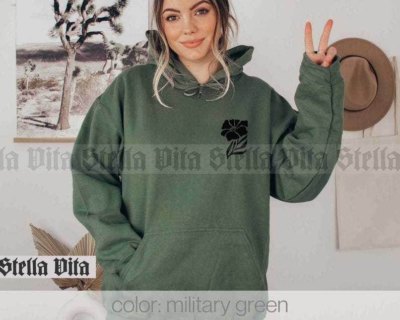 May include: A green hooded sweatshirt with a black floral design on the left chest. The text "color: military green" is at the bottom of the image.