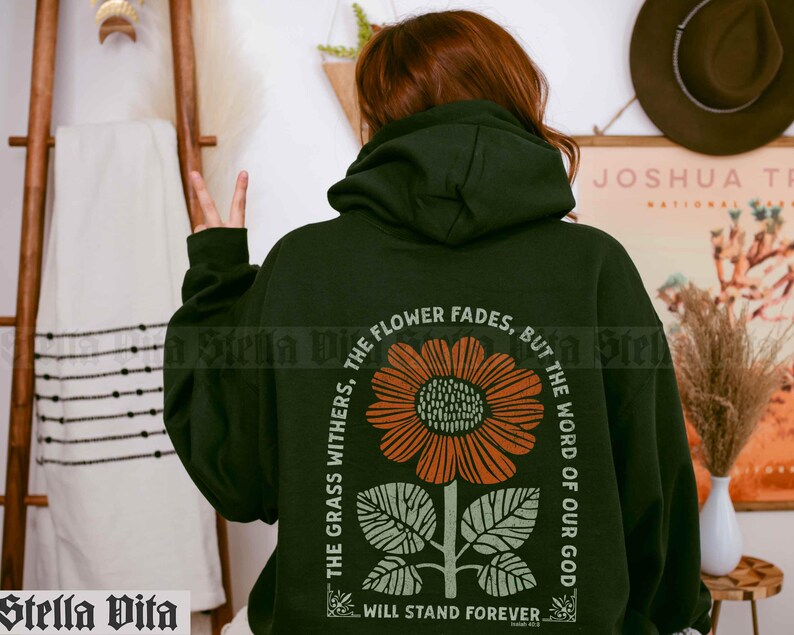 May include: A dark green hoodie with a floral graphic and the text "The grass withers, the flower fades, but the word of our God will stand forever."