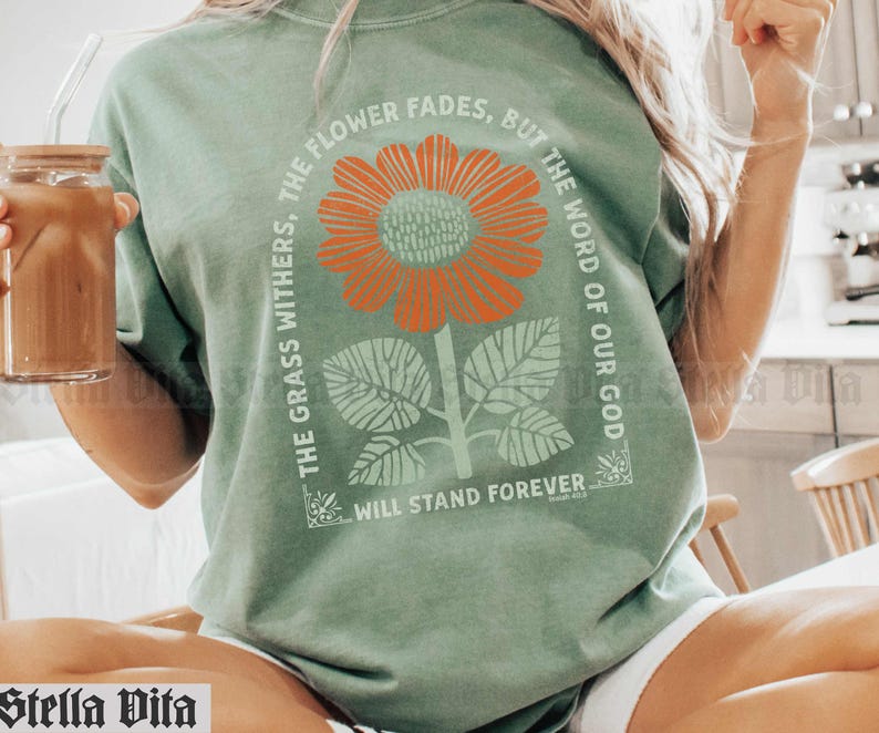 May include: A green t-shirt with a floral design and the text "The flower fades, but the word of our God, the grass withers, will stand forever".