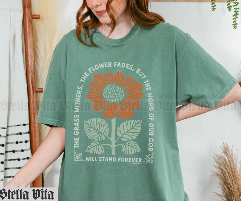 May include: Green t-shirt with a floral design and the text "The grass withers, the flower fades, but the word of our God will stand forever".