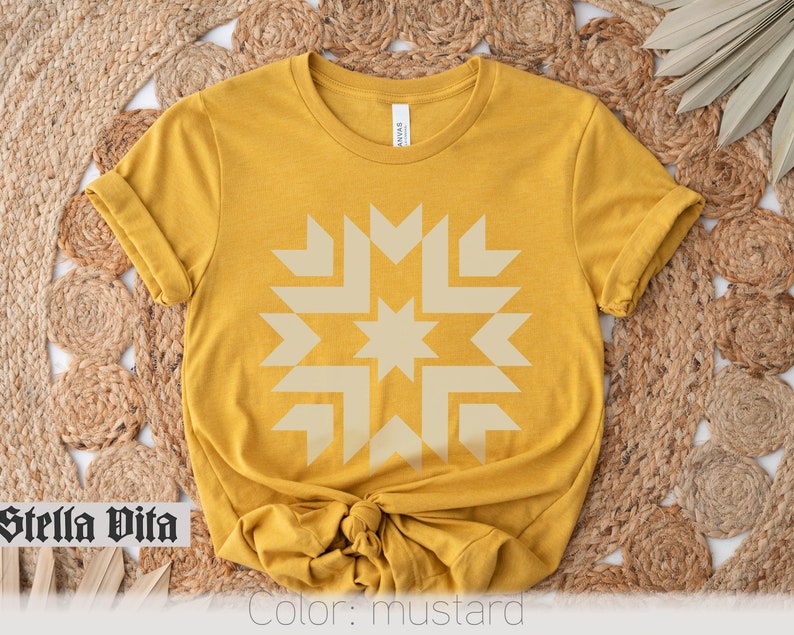 May include: A mustard yellow t-shirt with a beige geometric star design. The shirt is made of a soft, comfortable fabric and has a relaxed fit. "Stella Vita" is written in black text on the bottom left corner of the image. "Color: mustard" is written in black text on the bottom right corner of the image.