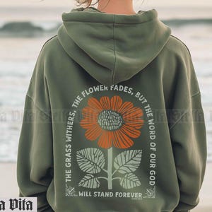 May include: Green hooded sweatshirt with a sunflower graphic and the text "The grass withers, the flower fades, but the word of our God will stand forever".